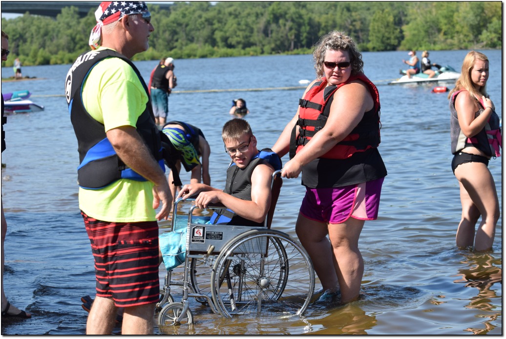 a female volunteer transferring a male skier out of the water in a wheelchair