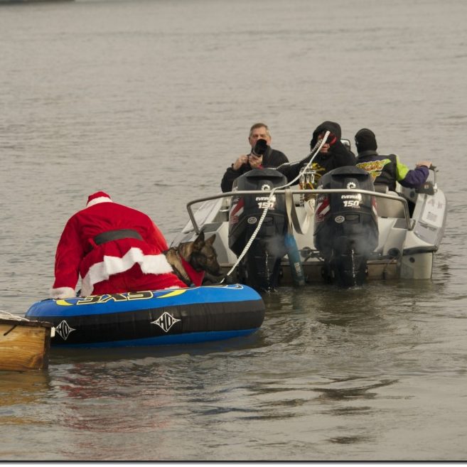 An adult male, dressed in a Santa suit, getting into a tube which will be pulled behind a boat on the Mississippi River